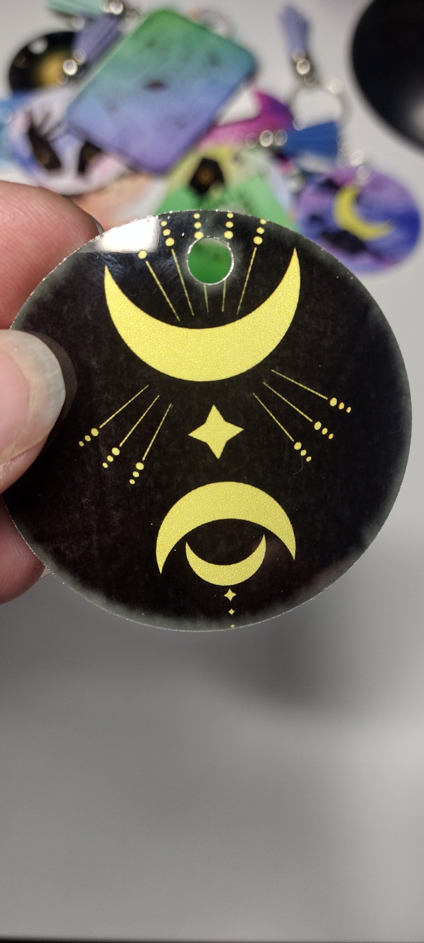 imperfect key chain design of crescent moons and geometric line with foggy coloring around the edges.