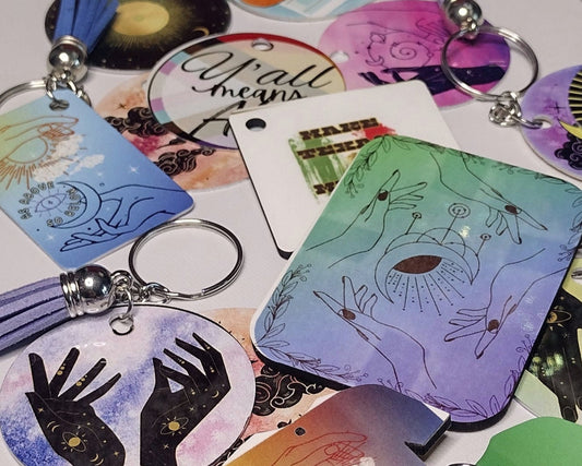 A pitched view of scattered, imperfect keychains of various sizes, with leather tassels of different colors hanging from the key rings.
